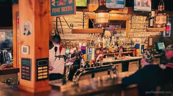 Interior del bar con barra de madera y estantería de botellas
