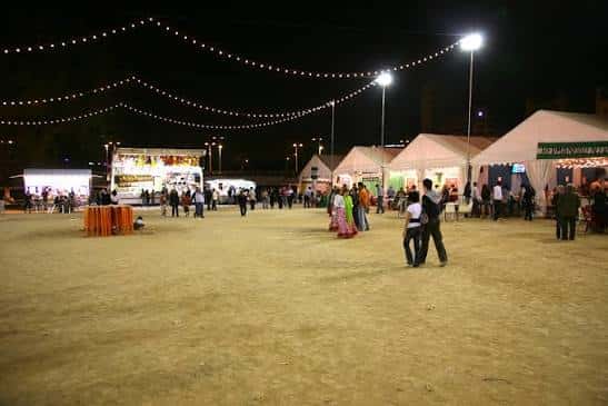 Plaza del recinto ferial con carpas y luces de cadena en la noche