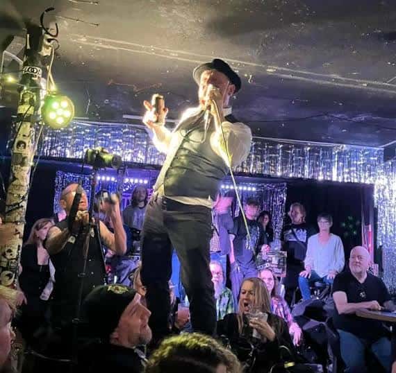 Concierto en vivo en The Lost Well con cantante en el escenario y público