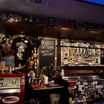 Barra del establecimiento con pegatinas, camisetas y letrero de eventos