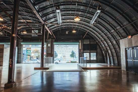 Interior del espacio de eventos con techo de bóveda metálica y suelo de concreto pulido