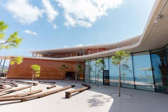 Fachada moderna del edificio con grandes ventanales y zona de descanso al aire libre