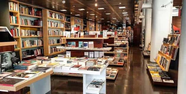 Interior de la librería con estanterías llenas de libros y mesas de exhibición