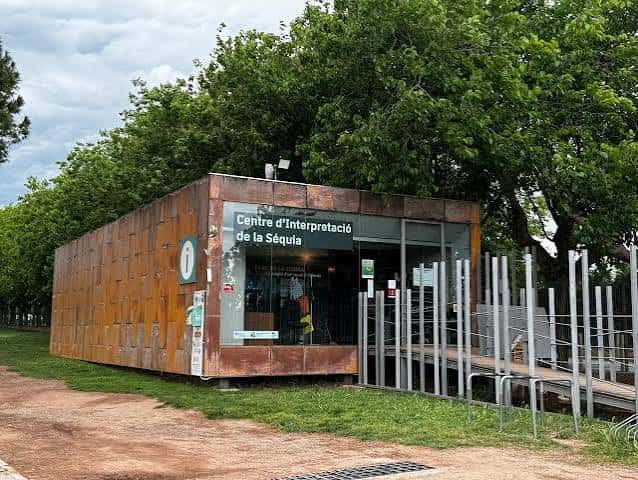 Fachada del Centre d'Interpretació de la Séquia con estructura metálica oxidada y entorno natural