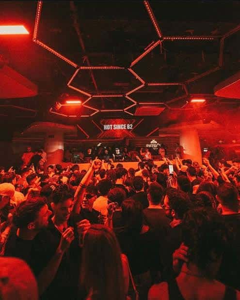 Interior del club KU Barcelona con iluminación roja y multitud bailando frente al DJ