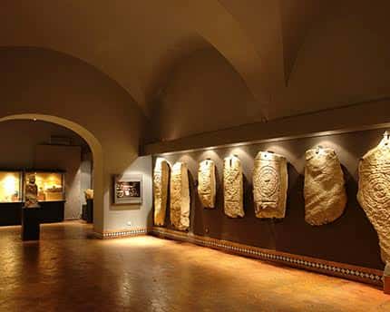 Galería de arte con relieves históricos iluminados bajo bóvedas
