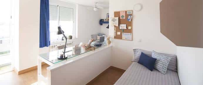 Interior de habitación universitaria con cama y escritorio