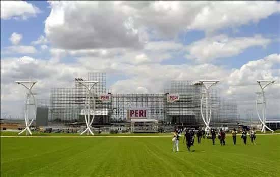 Vista panorámica del escenario en construcción con estructura metálica y césped frente a él