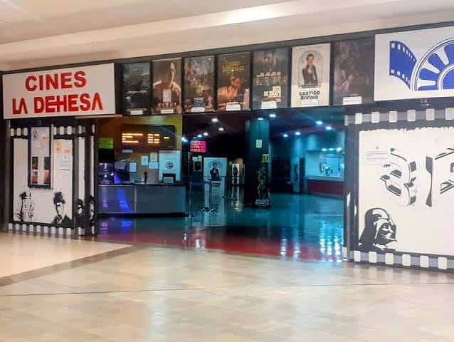 Vista general de la entrada principal de Cines La Dehesa con cartel luminoso y pósters de películas