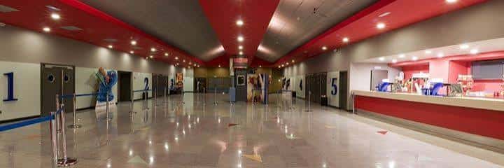 Interior del hall del cine con pasillos hacia las salas y taquilla a la derecha