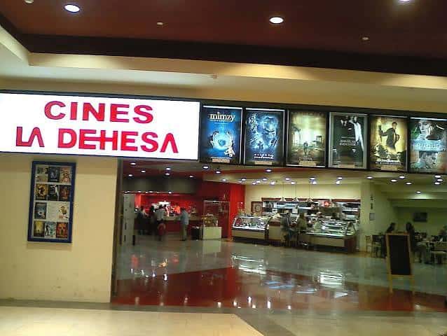 Entrada del cine mostrando el cartel luminoso, cartelera de películas y zona de cafetería