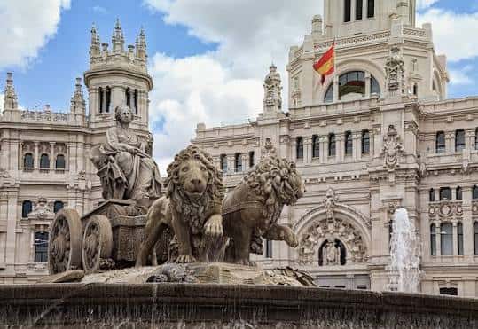 Primer plano de la escultura de la diosa Cibeles en su carro tirado por leones con el Palacio de Cibeles al fondo
