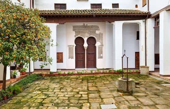 Entrada principal del convento con puerta de madera y jardín de naranjos