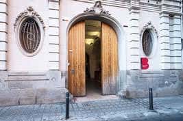 Fachada histórica del edificio con puerta de madera y detalles arquitectónicos