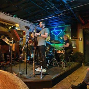 Banda en vivo actuando en el escenario del Elephant Room con iluminación azul
