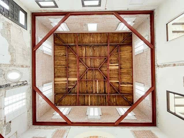 Interior del espacio con estructura de madera y techo de ladrillo visto