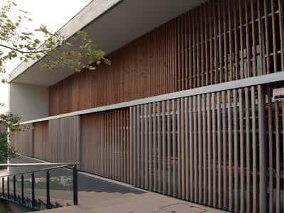 Detalle arquitectónico de la fachada con paneles de madera y barandilla metálica