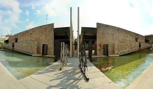 Vista panorámica de la fachada exterior de la Biblioteca Joan Miró con su característico diseño de piedra y canal de agua