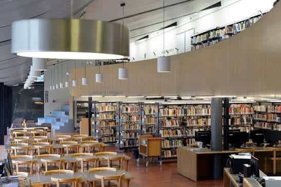 Interior de la sala de lectura con estanterías de libros, mesas de estudio y lámparas colgantes modernas