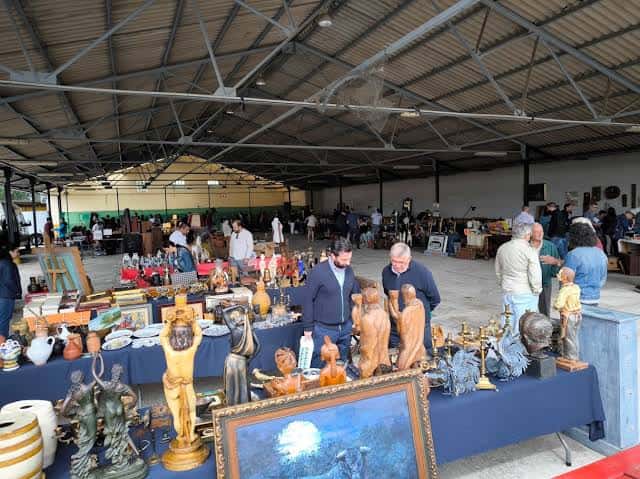Interior del recinto ferial durante una feria de antigüedades con puestos y público