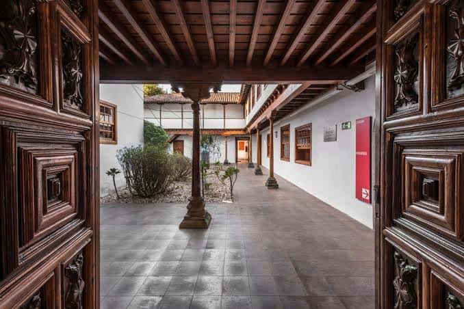 Vista del patio interior con columnas de madera y puertas talladas