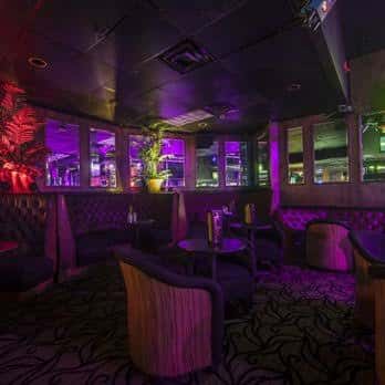 Sala de estar del club con luces púrpuras y decoración moderna