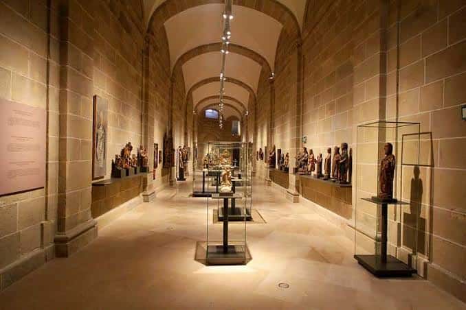 Galería principal del museo con bóvedas de piedra y vitrinas de arte sacro