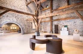 Sala de exposiciones con estructura de madera y paredes de piedra original