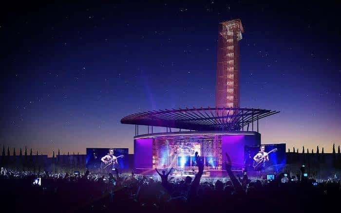 Vista nocturna del anfiteatro con el escenario iluminado y la torre característica