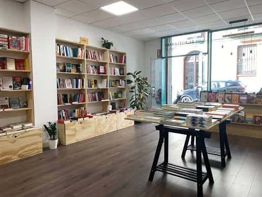 Vista interior de la librería con estanterías de madera y mesas de exposición