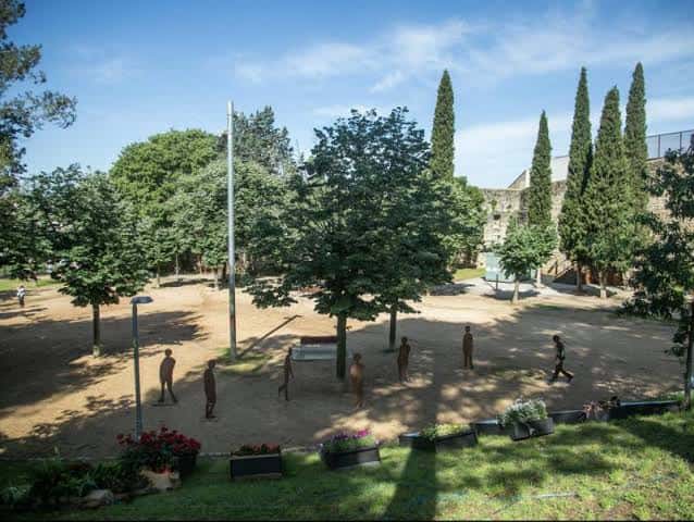Plaza arbolada con esculturas y bancos en los jardines