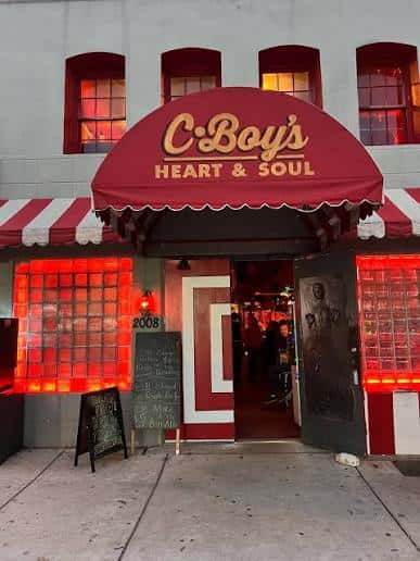 Fachada del local C-Boy's Heart & Soul con toldo rojo y luces de neón