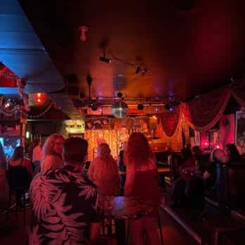 Interior del bar con ambiente festivo, luces de colores y personas disfrutando
