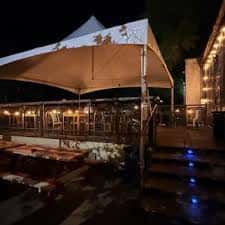 Terraza exterior con toldo blanco y mesas listas para eventos nocturnos