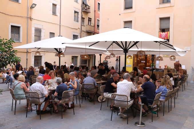 Terraza exterior de El Foment con mesas y sombrillas, ambiente festivo y acogedor