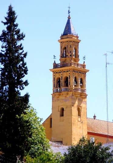 Detalle de la torre campanario de la iglesia con árboles en primer plano