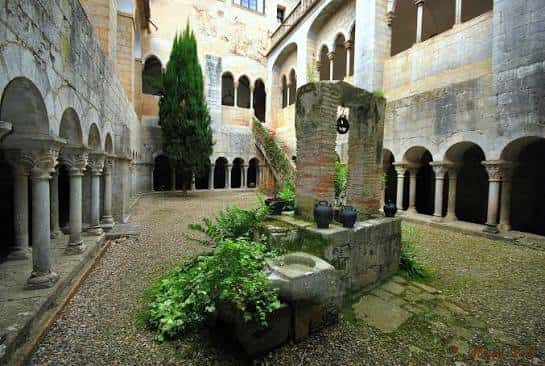Claustro del monasterio con arcos románicos y jardín central