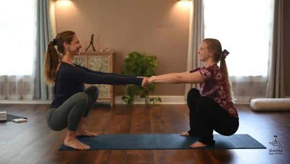 Dos personas practicando yoga en pareja en el estudio