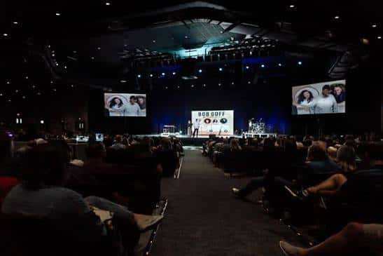 Interior del auditorio con público y pantalla durante un evento