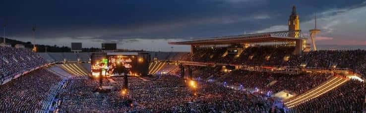 Concierto masivo en el Estadi Olímpic Lluís Companys con escenario iluminado y multitud en las gradas