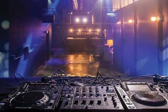 Vista desde la cabina de DJ hacia el escenario y la barra