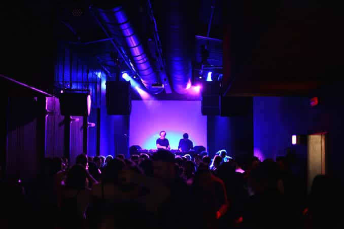 Evento en vivo con público y DJ en el escenario bajo luces de neón