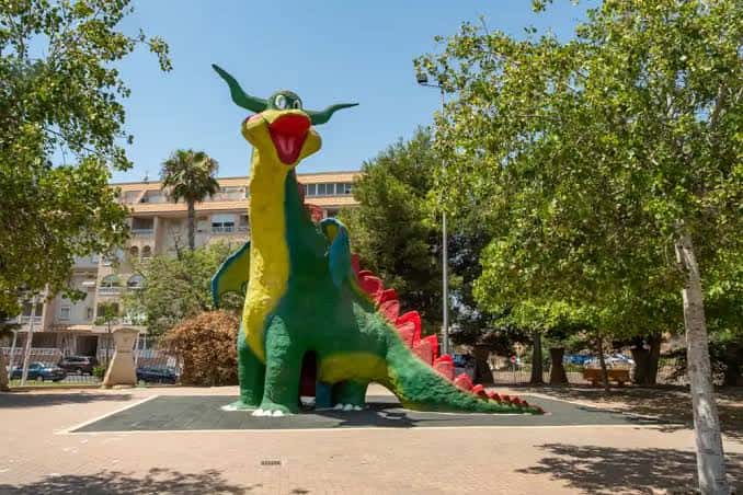 Escultura colorida de un dragón en el área infantil del parque