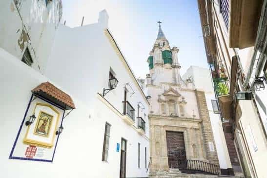 Vista exterior de la Iglesia de Santa María en Cádiz, mostrando su fachada blanca y campanario