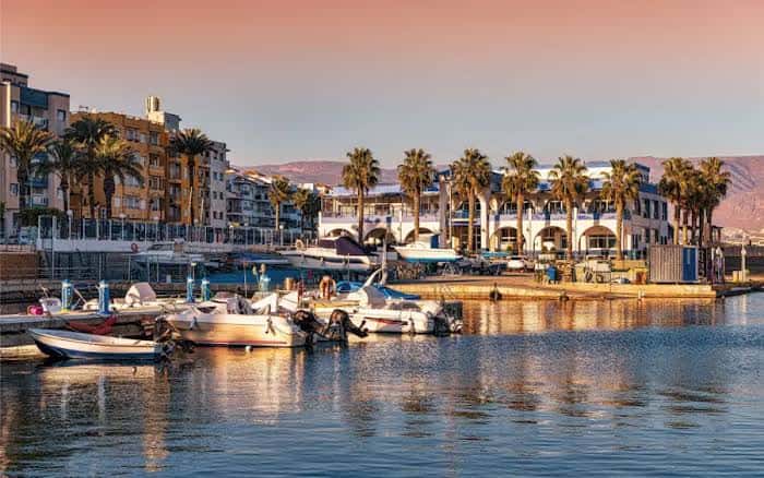 Puerto de Roquetas de Mar con palmeras y edificios al atardecer