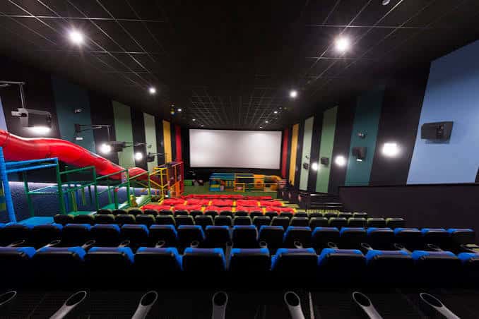 Sala de cine con pantalla grande y zona de juegos infantil