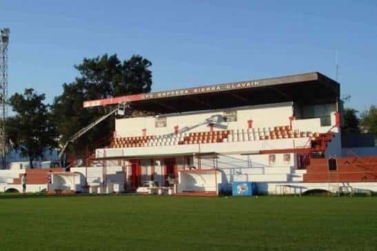 Gradas del estadio con asientos naranjas y blancos bajo un cielo despejado