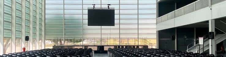 Interior del auditorio de Ifeza con butacas negras y pantalla central en un espacio amplio y luminoso