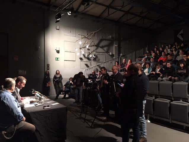 Evento en el auditorio con público y mesa de prensa