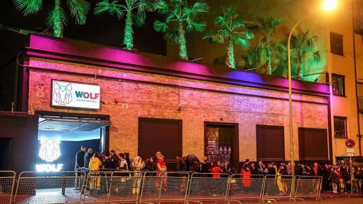Fachada exterior de la Sala Wolf en Barcelona por la noche con luces de neón y cola de asistentes